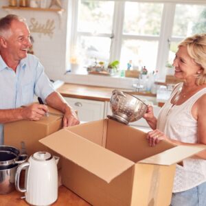 elderly couple putting kitchen items into boxes