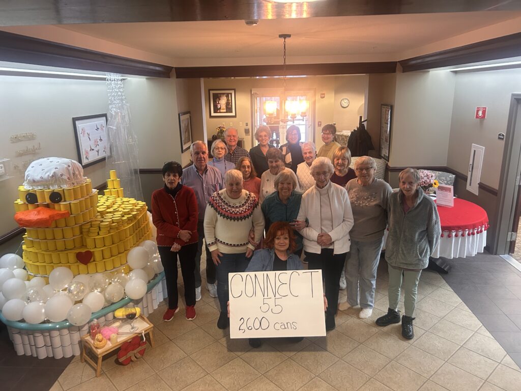 group of senior citizens pose with their can competition entry that won at their senior living complex