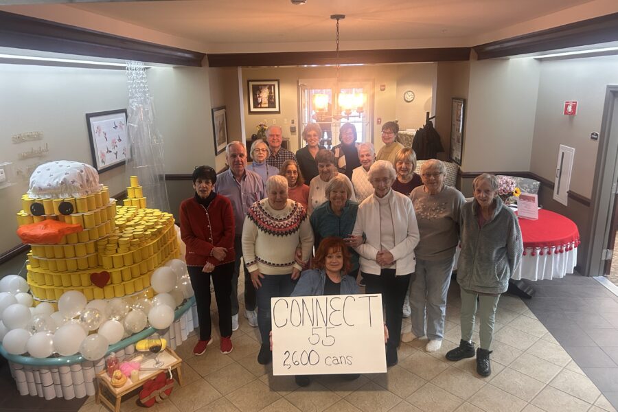 group of senior citizens pose with their can competition entry that won at their senior living complex